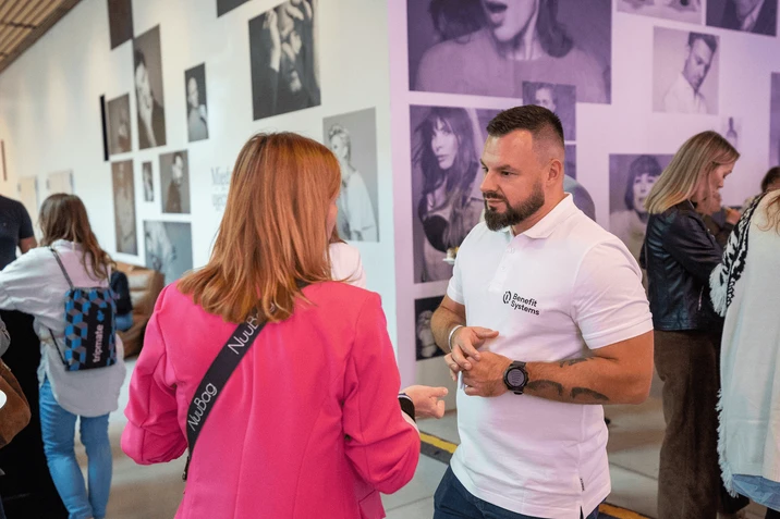 Pracownicy rozmawiają podczas wydarzenia firmowego w nowoczesnej przestrzeni biurowej z artystycznymi zdjęciami na ścianach