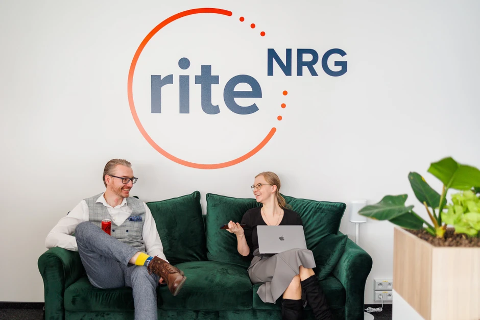 Dwóch pracowników rozmawia na zielonej kanapie w biurze firmy Rite NRG w nowoczesnym wnętrzu