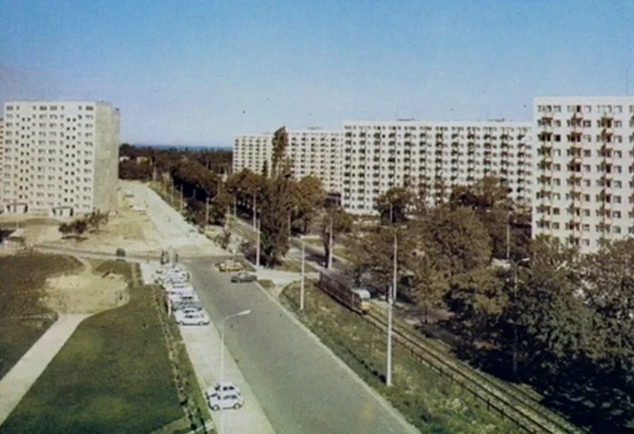 Widok na osiedle z wielorodzinnymi blokami i zielenią w otoczeniu ulic oraz torów tramwajowych