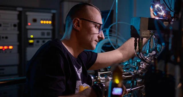 Inżynier precyzyjnie pracujący przy zaawansowanym sprzęcie elektronicznym w laboratorium technicznym