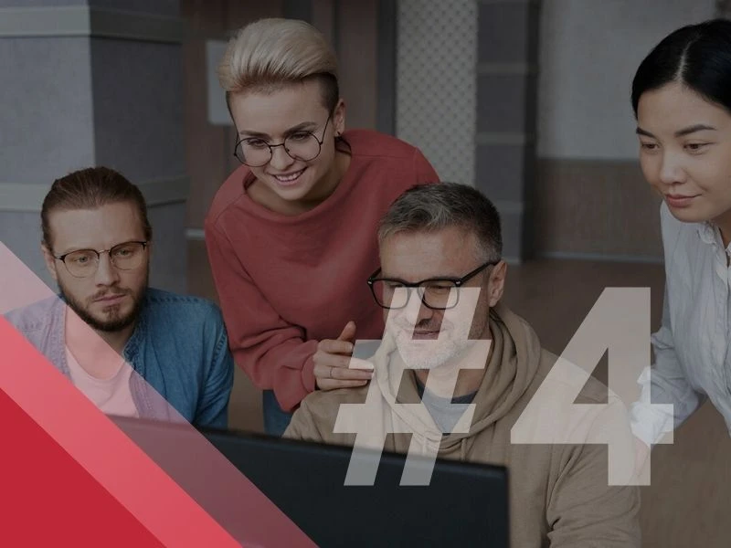 Zespół czterech osób pracujących wspólnie przy komputerze w nowoczesnym biurze