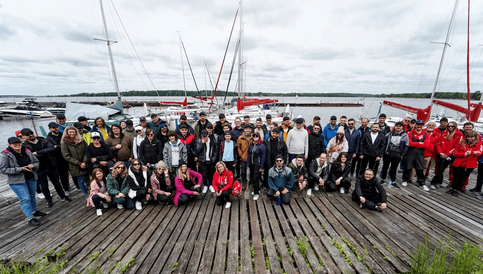 Duża grupa pracowników podczas integracyjnego spotkania na molo nad jeziorem przy jachtach