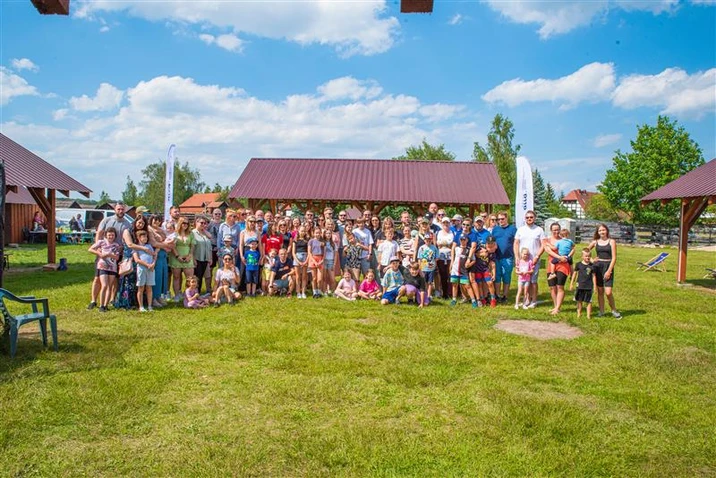 Duża grupa pracowników i ich rodzin spotyka się na firmowej imprezie integracyjnej na świeżym powietrzu