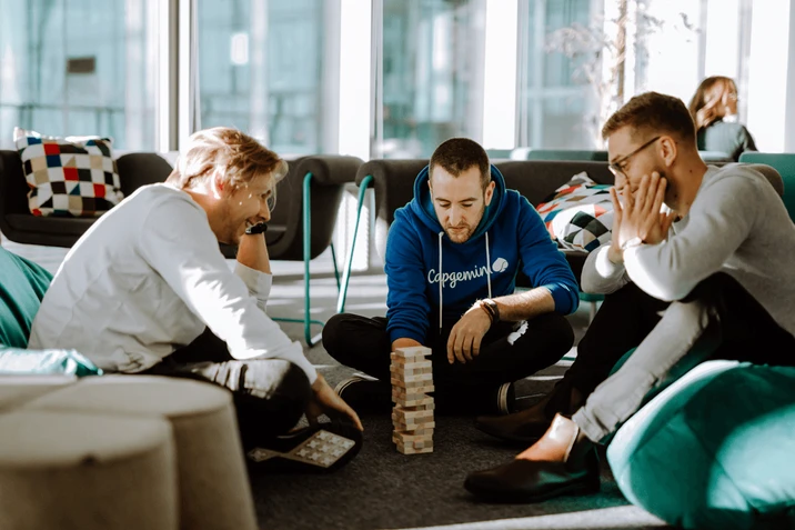 Trzech pracowników w przestrzeni biurowej gra w Jengę, spędzając czas na relaksie i integracji