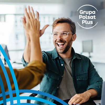 Dwóch współpracowników Grupy Polsat Plus świętuje sukces pracując wspólnie w nowoczesnym biurze