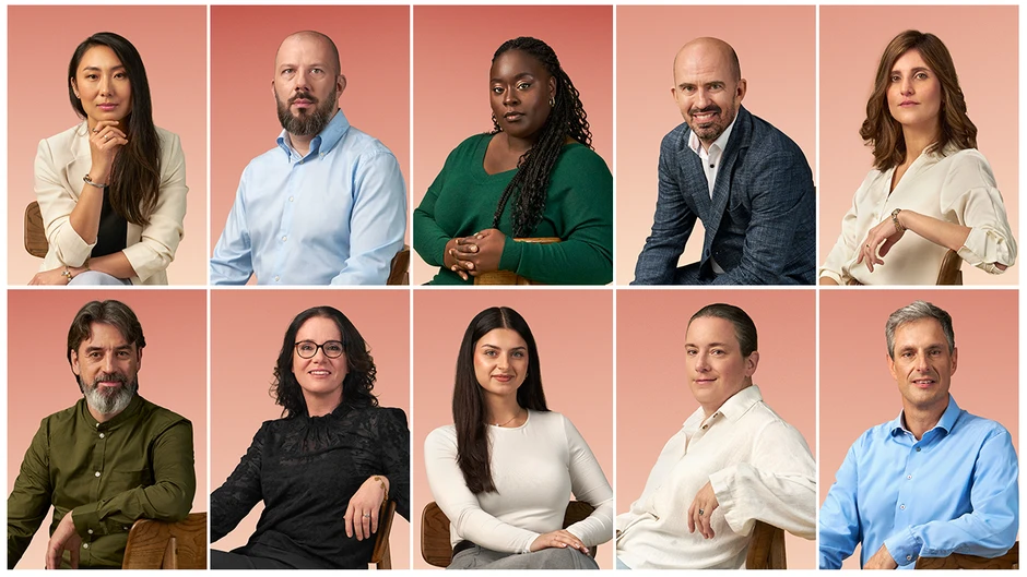 Zespół dziesięciu profesjonalistów w różnym wieku pozujących na jednolitym różowym tle