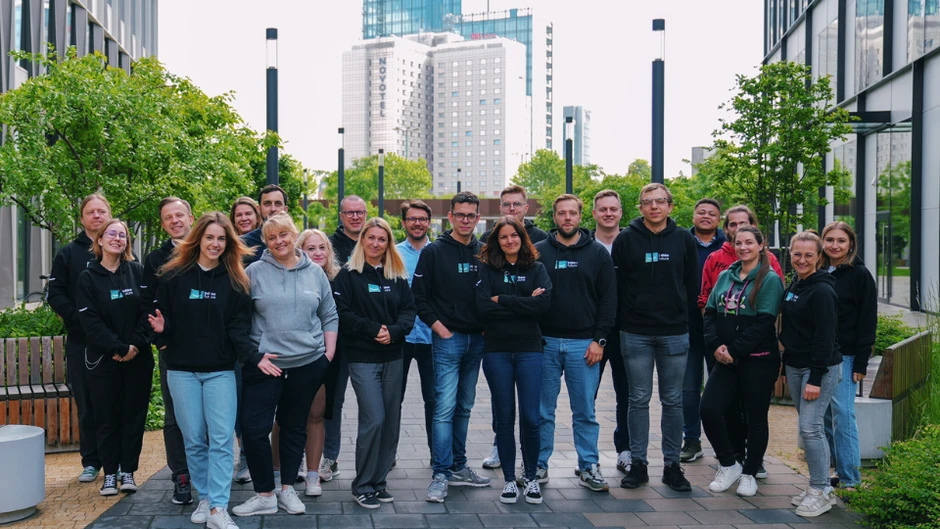 Zespół pracowników pozujący na zewnątrz biura w nowoczesnym otoczeniu miejskim, przyjazna atmosfera