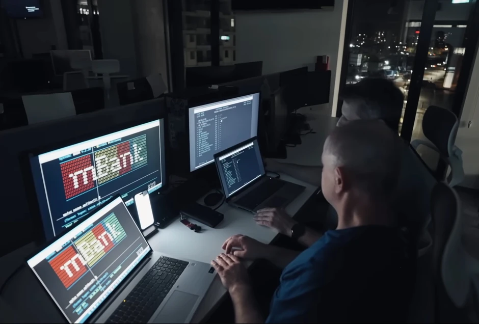 Dwóch mężczyzn intensywnie pracuje przy komputerach w nowoczesnym biurze podczas nocnej zmiany