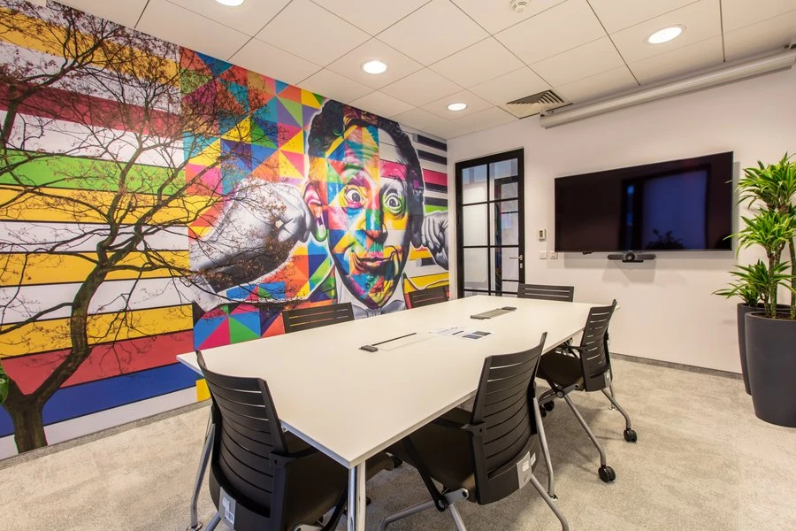 Nowoczesna sala konferencyjna z kolorowym muralem ściennym i dużym stolikiem do spotkań zespołowych