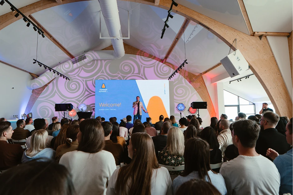 Widok z tyłu na salę konferencyjną pełną uczestników słuchających prelegenta na Summer Summit