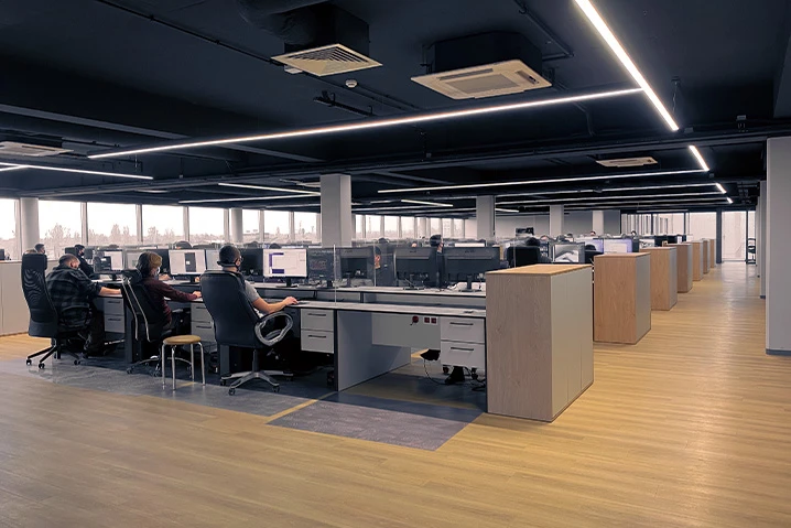 Nowoczesne biuro open space z pracownikami przy komputerach w przestronnym i jasnym wnętrzu