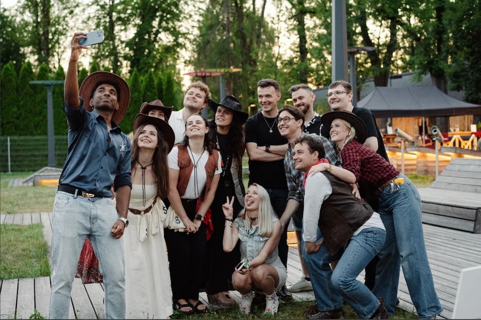 Grupa pracowników ubranych w kowbojskie stroje robi wspólne zdjęcie selfie podczas integracji na świeżym powietrzu