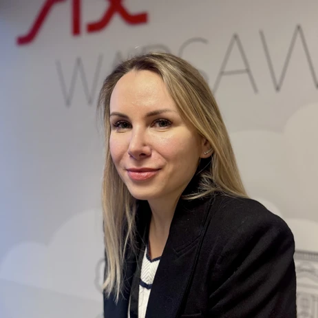 Portret uśmiechniętej kobiety w średnim wieku w biurowym otoczeniu na tle napisu Warsaw