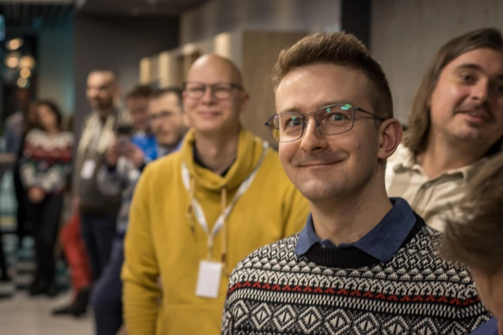 Grupa uśmiechniętych pracowników w luźnej atmosferze biurowej podczas spotkania zespołu