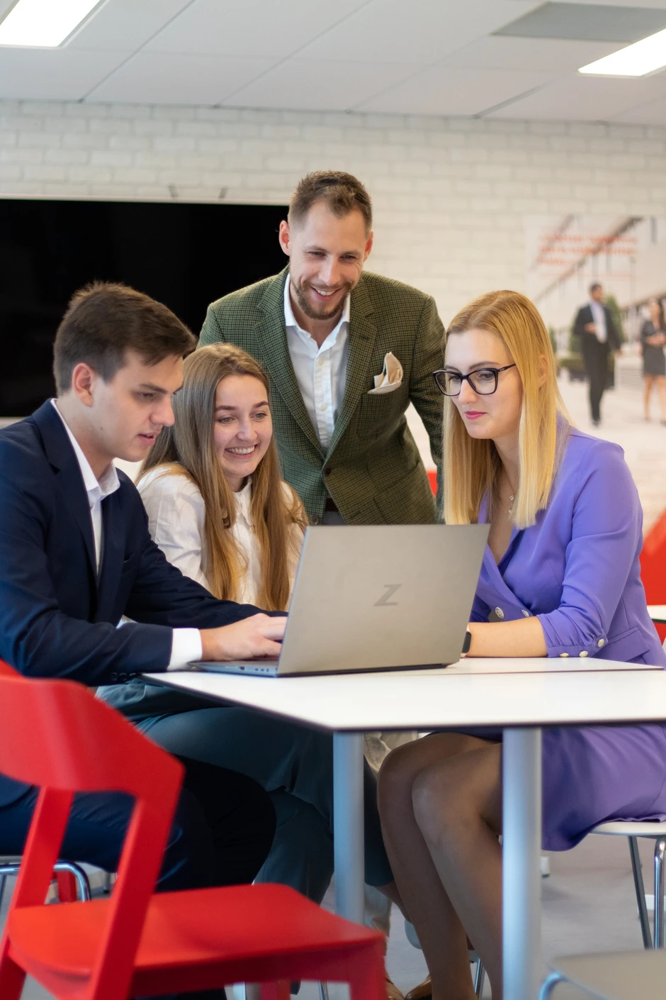 Zespół młodych profesjonalistów pracuje wspólnie przy laptopie w nowoczesnym biurze o żywej atmosferze