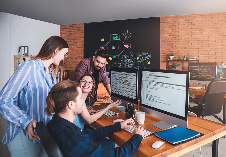 Zespół programistów współpracuje w nowoczesnym biurze nad kodem na monitorach w kreatywnej atmosferze