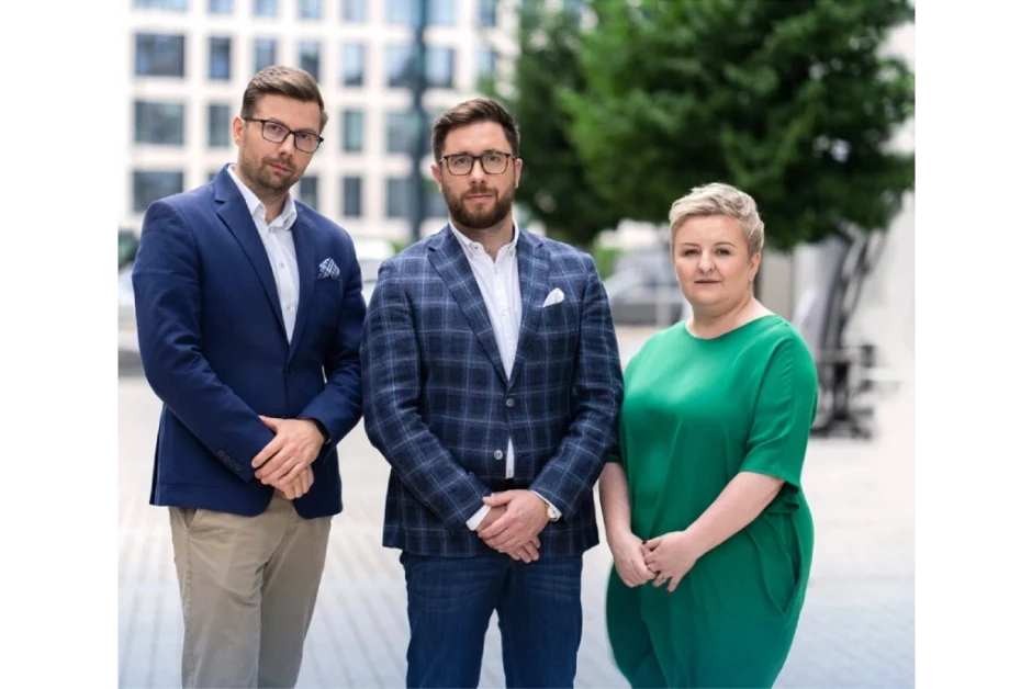 Trójka profesjonalistów w eleganckich strojach stoi na tle nowoczesnego biurowca na zewnątrz