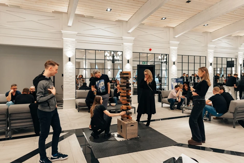 Pracownicy w nowoczesnym biurze grają w dużą drewnianą Jengę podczas firmowego spotkania integracyjnego