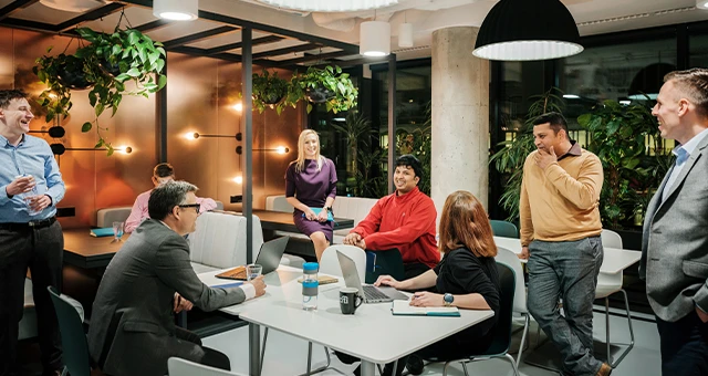 Zespół pracowników w nowoczesnym biurze podczas nieformalnego spotkania i rozmów przy stole