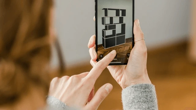 Osoba używa smartfona do projektowania cyfrowych mebli w rzeczywistości rozszerzonej w nowoczesnym wnętrzu