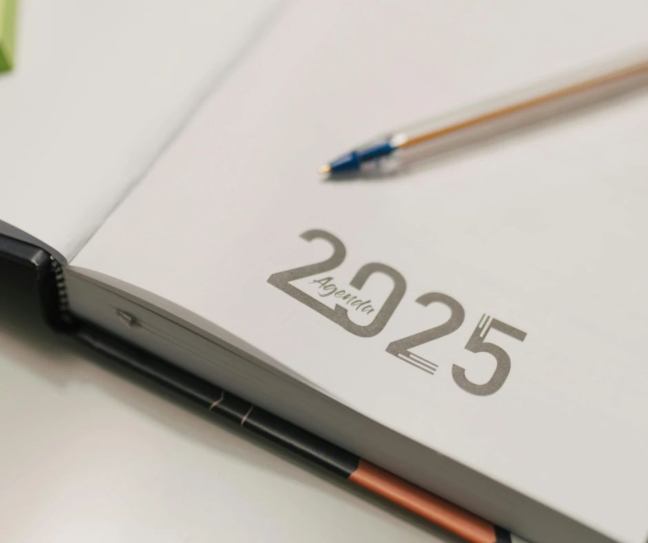 Otwarty kalendarz na rok 2025 z długopisem na białym biurku, gotowy do planowania