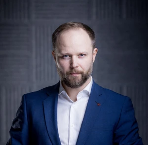 Portret mężczyzny w garniturze i białej koszuli na tle nowoczesnej, ciemnej ściany w stylu biznesowym