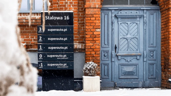 Wejście do biurowca przy Stalowej 16 z niebieskimi drzwiami i tablicą informacyjną firm superauto.pl