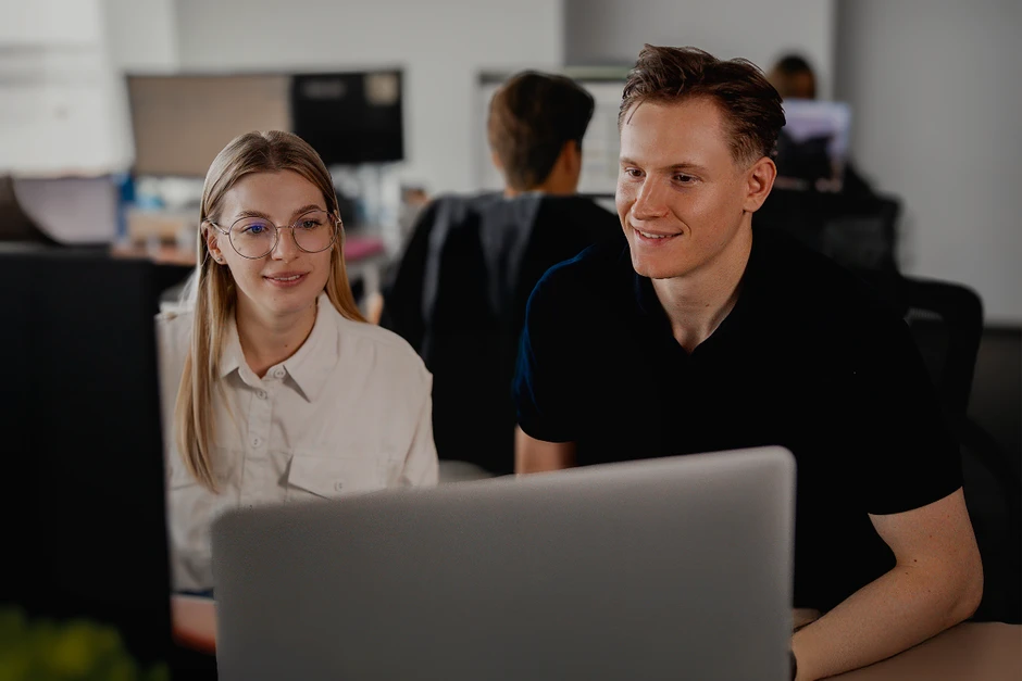 Dwoje młodych pracowników współpracuje przy komputerze w nowoczesnym biurze pełnym zaangażowania