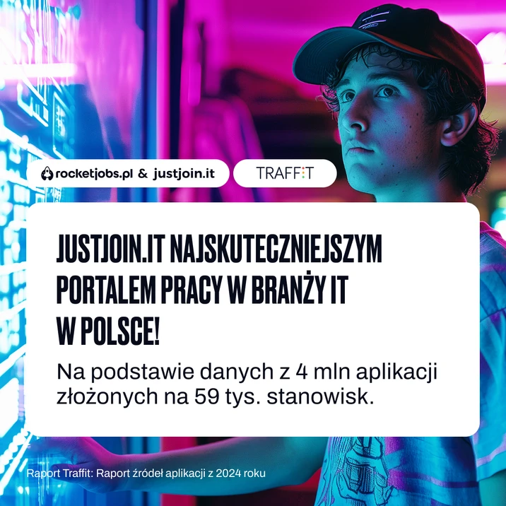 Młody mężczyzna w czapce stoi przy ekranie z kolorowym oświetleniem w nowoczesnym biurze IT