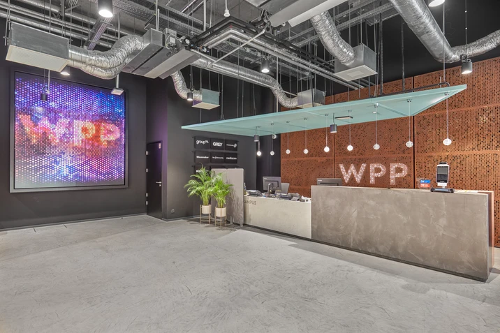 Nowoczesne biuro z minimalistycznym recepcją i dużym cyfrowym ekranem z logo WPP