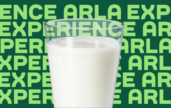 Szklanka białego mleka na tle zielonym z powtarzającym się napisem EXPERIENCE ARLA