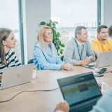 Grupa osób siedząca przy stole podczas spotkania biznesowego w nowoczesnym biurze