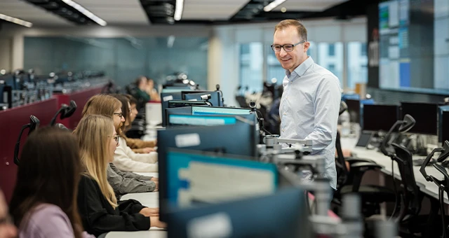 Zespół pracowników w nowoczesnym biurze podczas wspólnej pracy przy komputerach pod kierunkiem menedżera