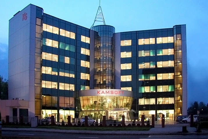 Nowoczesny budynek biurowy KAMSOFT z podświetlonymi oknami wieczorem w miejskiej scenerii