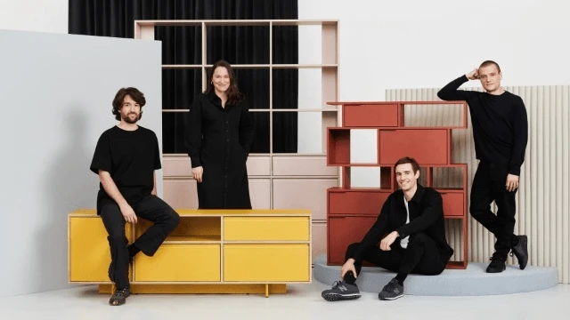 Cztery osoby pozują na tle nowoczesnych mebli w minimalistycznym wnętrzu firmy