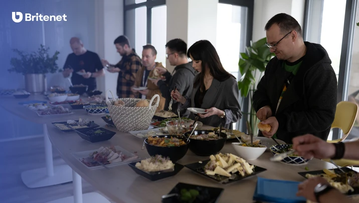 Pracownicy Britenet podczas wspólnego posiłku w jasnym biurze z bufetem pełnym jedzenia