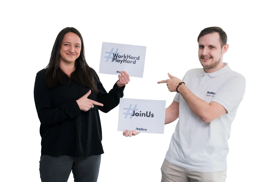 Dwóch uśmiechniętych pracowników firmy Andea trzyma tabliczki z hasłami Work Hard Play Hard i Join Us