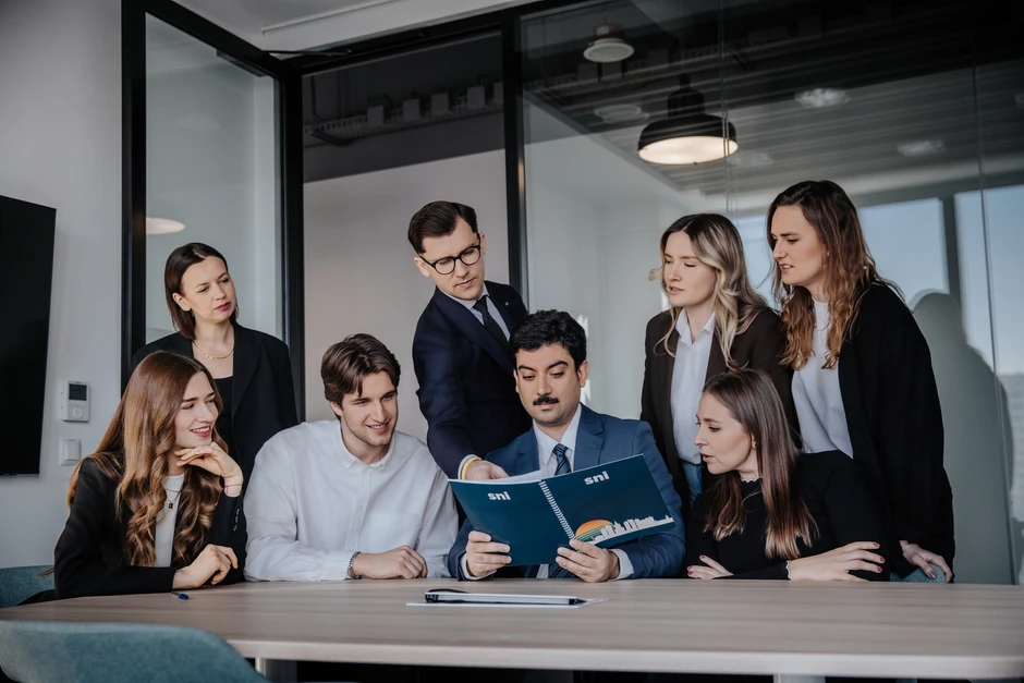 Grupa młodych profesjonalistów dyskutuje nad dokumentem podczas spotkania w nowoczesnej sali konferencyjnej
