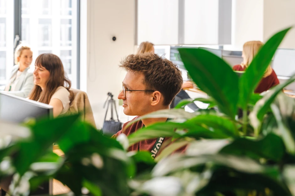 Pracownicy w nowoczesnym biurze rozmawiają i pracują przy komputerach w jasnym pomieszczeniu