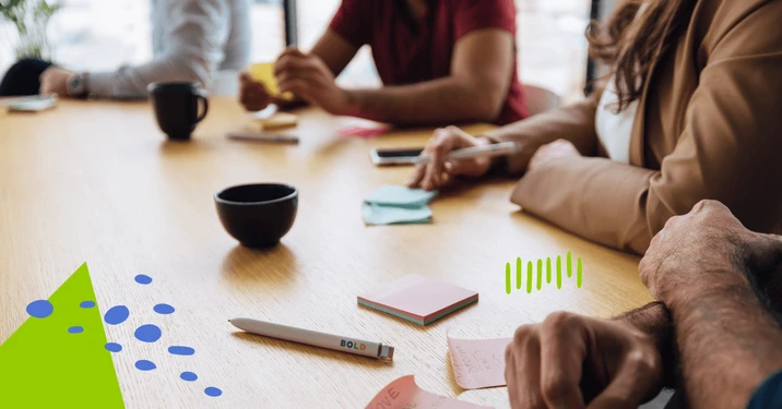 Zespół pracowników podczas burzy mózgów przy stole z notatkami i kubkami kawy w nowoczesnym biurze